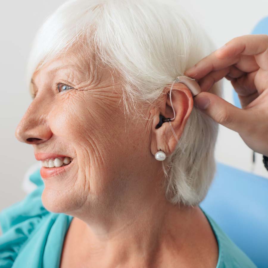 woman putting on earring aids